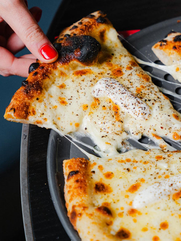 Cacio e Pepe pizza with slice being pulled out to reveal a cheese pull