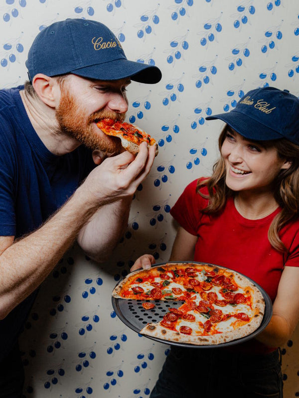 A smiling man and woman on a date eating pizza at Pizzana