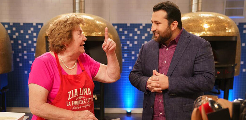 A Nonna contestant talking with Chef Daniele Uditi on the set of Hulu’s Best in Dough