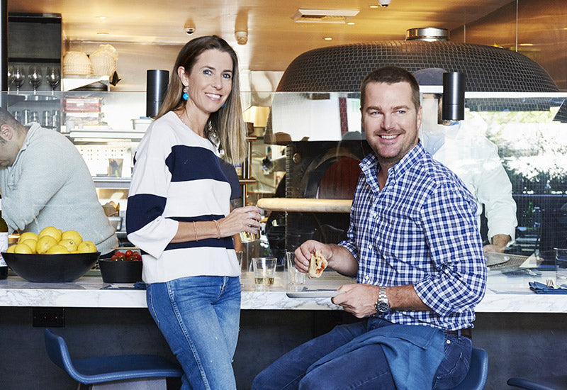 Pizzana partners Caroline and Chris O’Donnell holding wine and pizza at Pizzana Brentwood