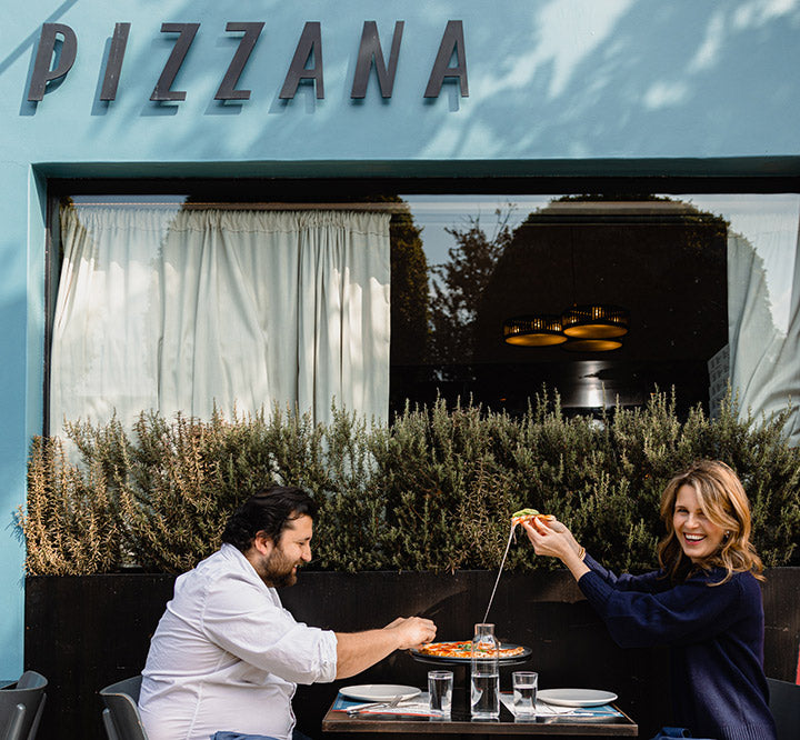 Pizzana founder Candace Nelson and Chef Daniele Uditi sharing a Margherita pizza outside Pizzana West Hollywood