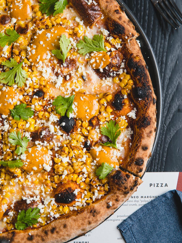 Elote di Strada pizza with wood fired bell pepper ranchero, queso oaxaca, charred corn, chipotle crema, cotija cheese and cilantro