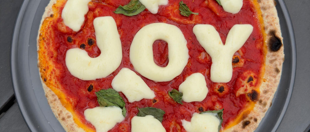 Merry Margherita pizza with JOY written in fior di latte letters for the holidays