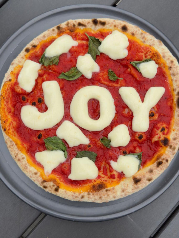 Merry Margherita pizza with JOY written in fior di latte letters for the holidays