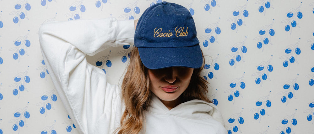 Woman wearing Pizzana Home of the Cacio e Pepe hoodie and Cacio Club hat