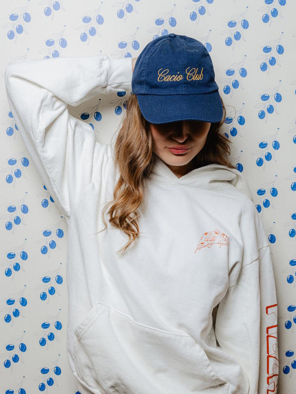 Woman wearing Pizzana Home of the Cacio e Pepe hoodie and Cacio Club hat