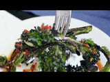 Video of fork lifting piece of wood fired Broccolini over plate 