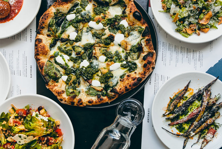 An assortment of Italian dishes including Spinaci pizza, salad and vegetables