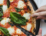 Hand taking a slice of Margherita pizza